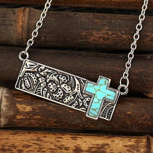 a silver cross with a turquoise cross on it