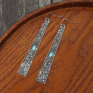 a pair of earrings sitting on top of a wooden table