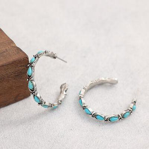 a pair of silver hoop earrings with turquoise stones