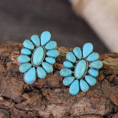 a pair of turquoise stone earrings sitting on top of a rock