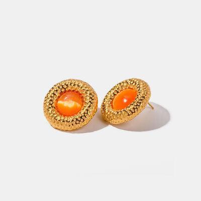 a pair of gold earrings with an orange stone