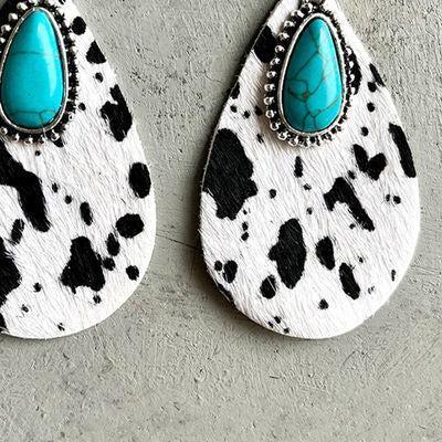 a pair of cow print earrings with turquoise stones