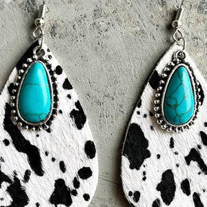 a pair of white and black earrings with turquoise stones