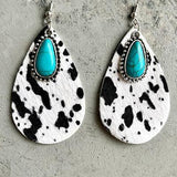 a pair of white and black earrings with turquoise stones