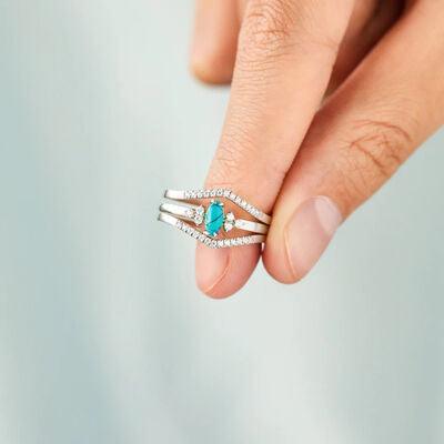 a woman's hand holding a ring with a turquoise stone