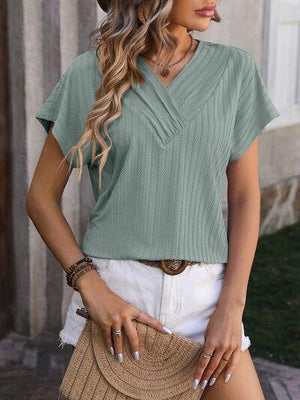 a woman wearing a green top and white shorts