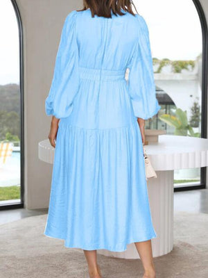 a woman in a blue dress standing in front of a window