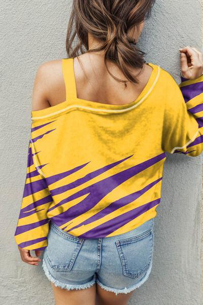 a woman in a yellow and purple shirt leaning against a wall