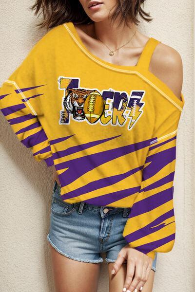 a woman in a yellow and purple shirt leaning against a wall