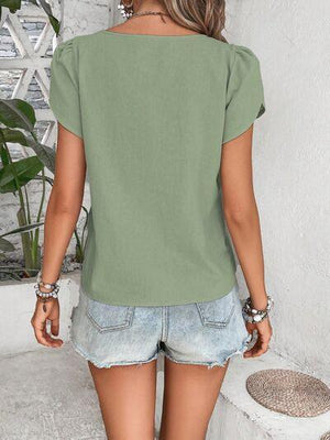 a woman wearing a green top and denim shorts