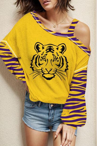 a woman in a yellow tiger shirt leaning against a wall