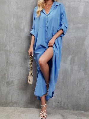 a woman in a blue shirt dress leaning against a wall
