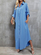 a woman in a blue shirt dress standing against a wall