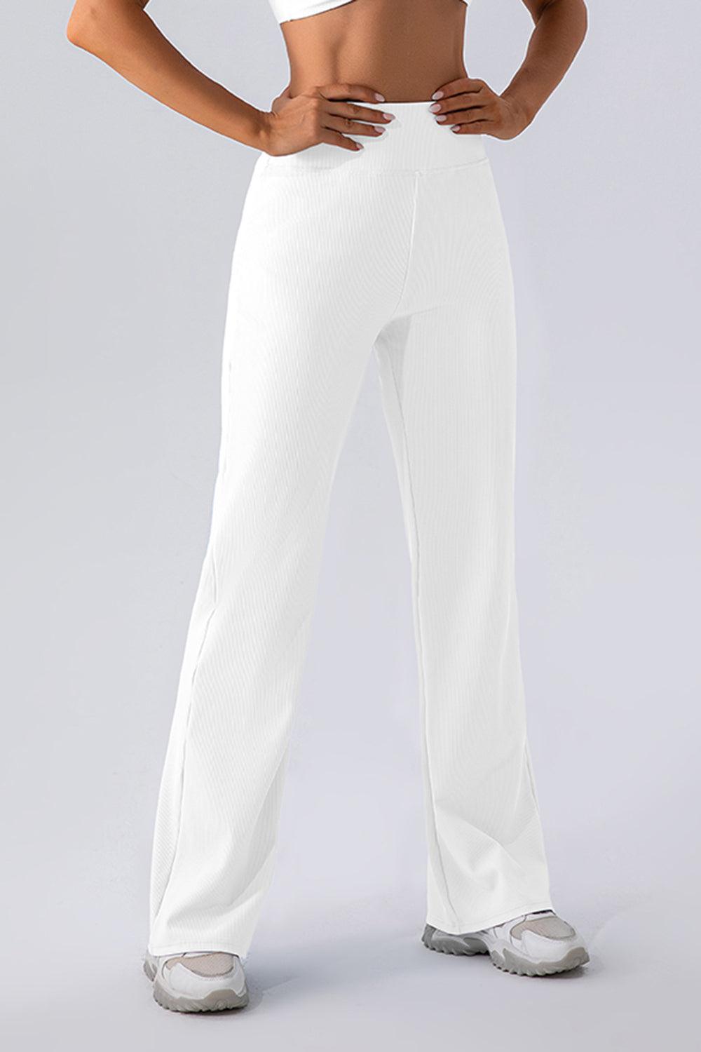 a woman wearing white pants and a crop top