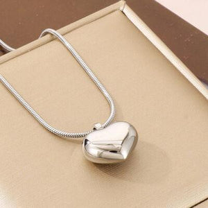 a silver heart shaped pendant sitting on top of a box