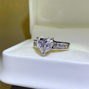 a heart shaped diamond ring sitting on top of a white box