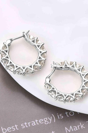 a pair of silver hoop earrings sitting on top of a white plate