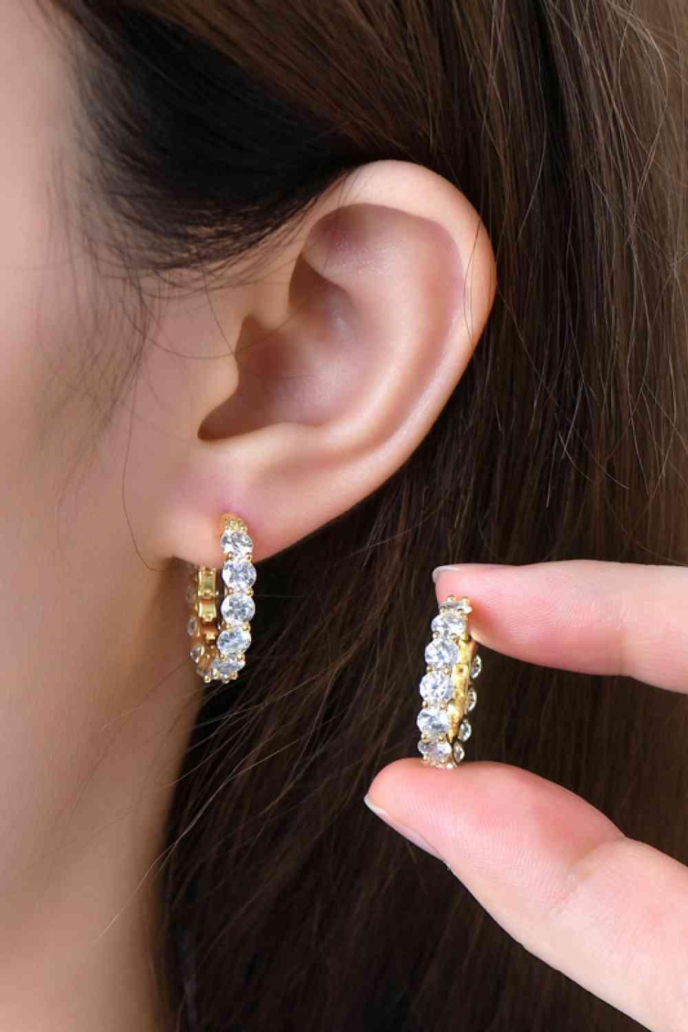 a woman's hand holding a pair of earrings