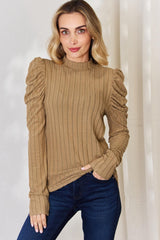 a woman wearing a brown sweater and jeans