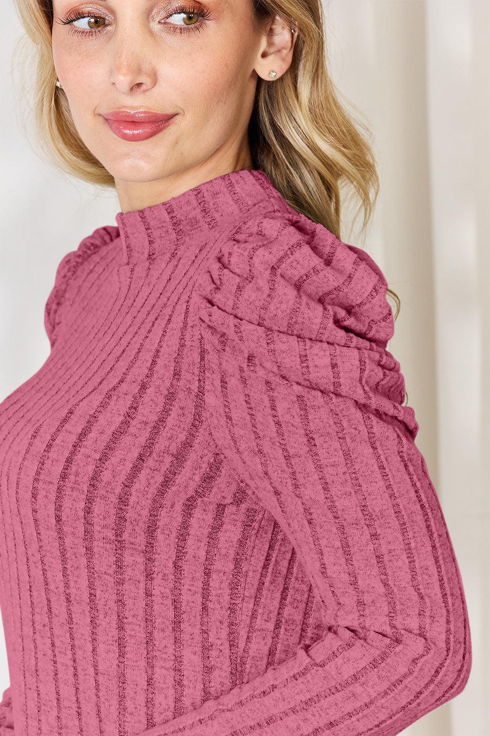 a woman with blonde hair wearing a pink sweater