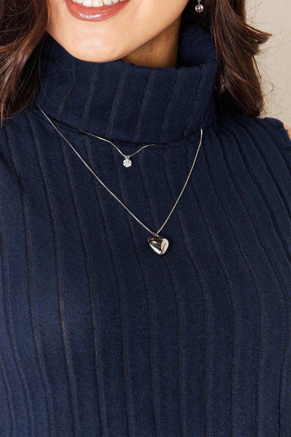 a close up of a woman wearing a sweater and a necklace