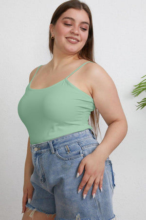 a woman wearing a green tank top and denim shorts