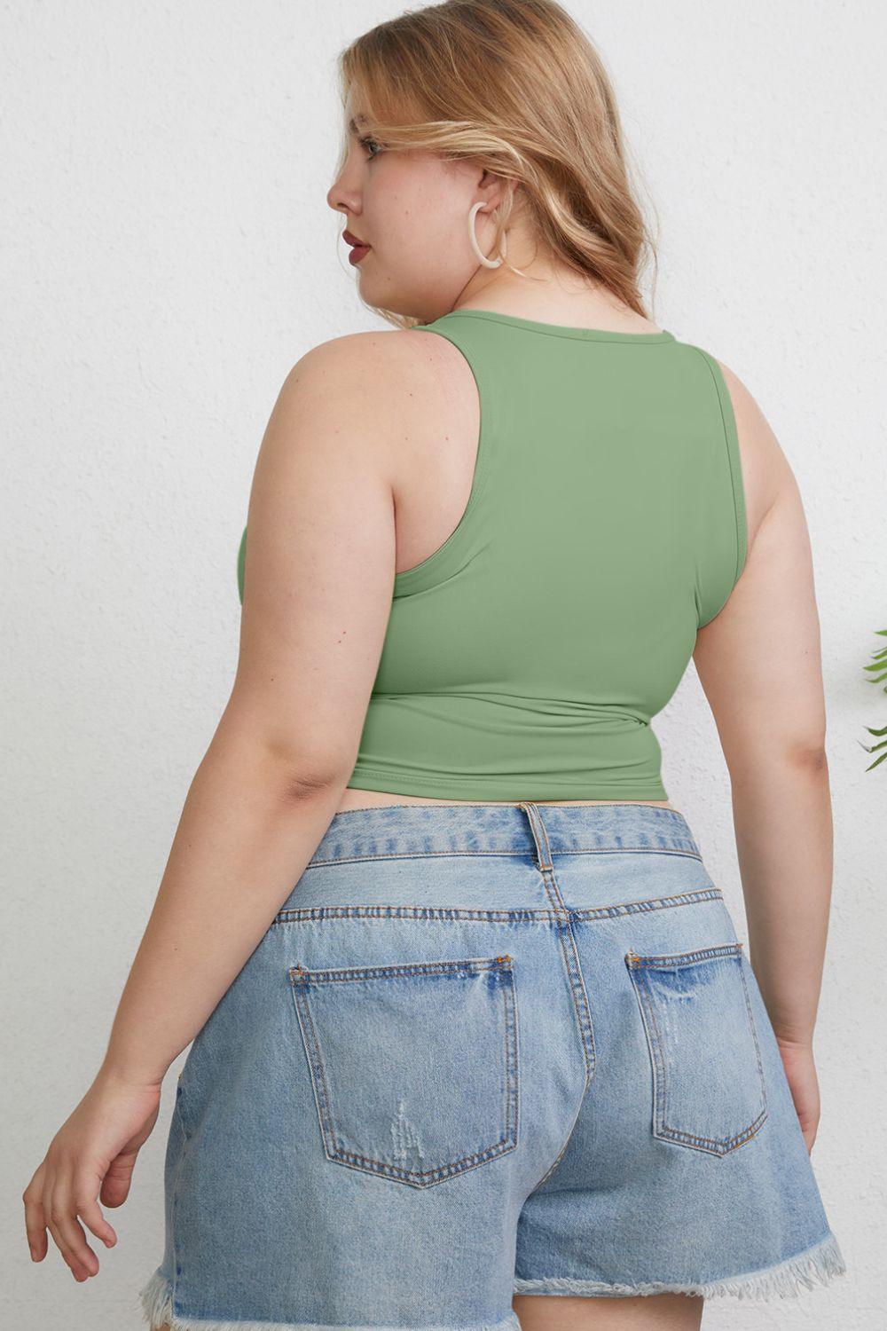 a woman wearing a green tank top and denim shorts