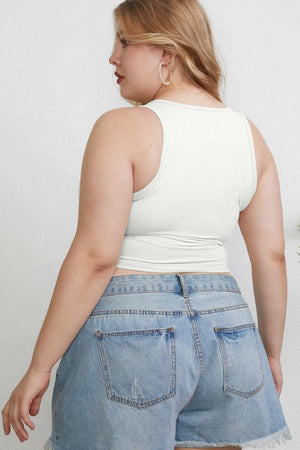 a woman in a white tank top and denim shorts