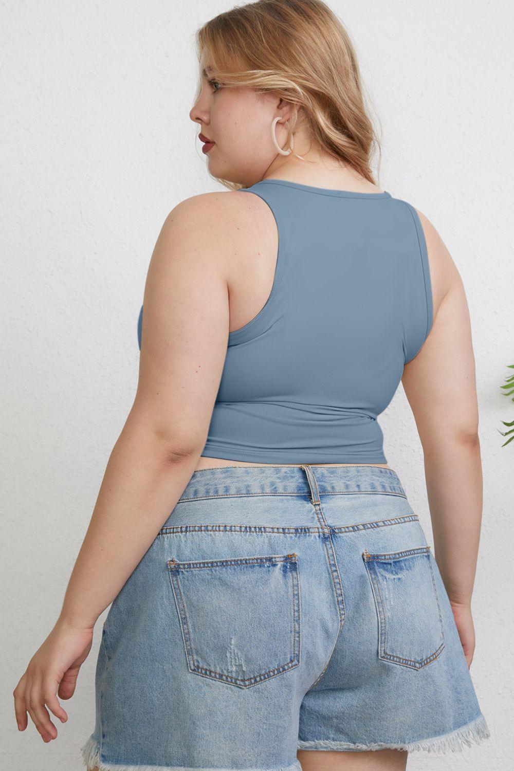 a woman wearing a blue tank top and denim shorts