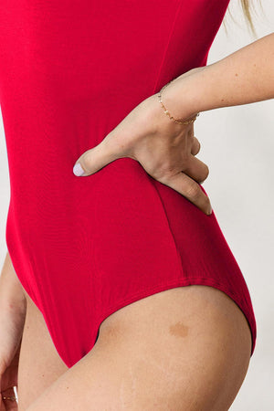 a woman in a red bodysuit with her hand on her hip