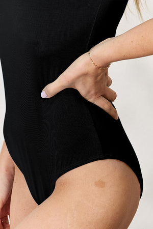 a woman in a black bodysuit with her hand on her hip
