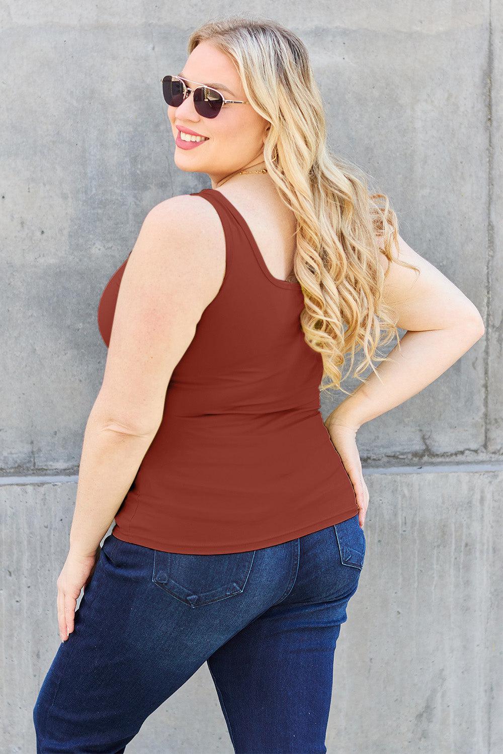a woman wearing a brown tank top and jeans