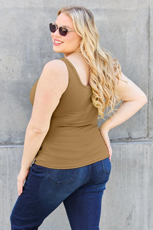 a woman wearing a tan tank top and jeans
