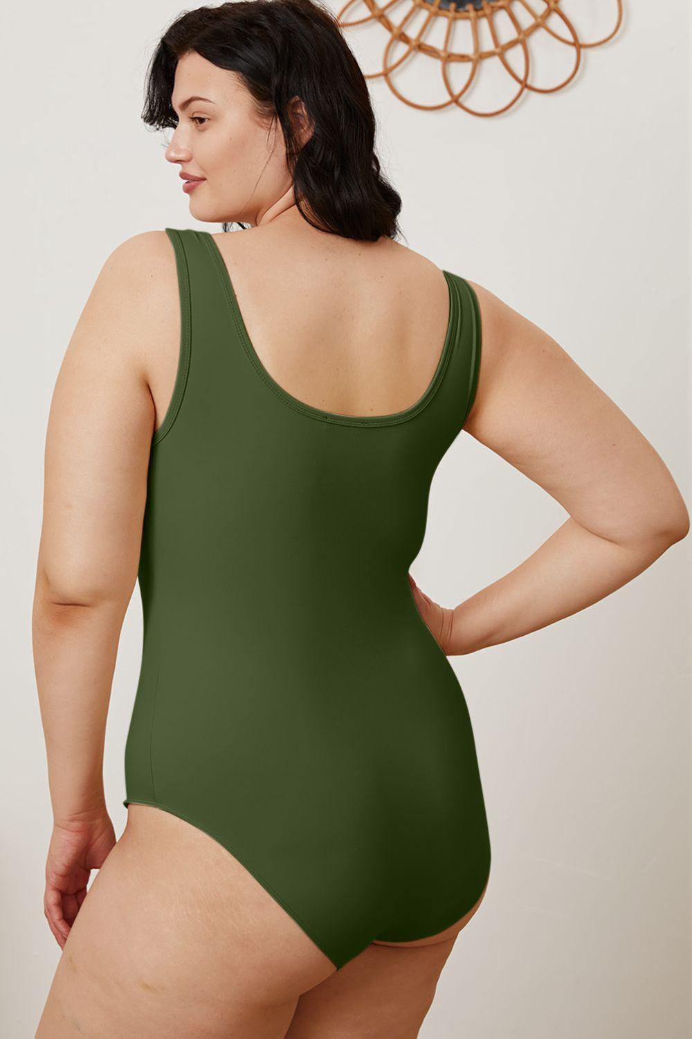 a woman in a green bodysuit with her hands on her hips