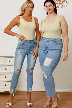 two women standing next to each other in jeans