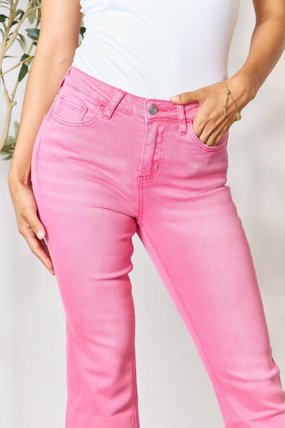 a woman in a white tank top and pink jeans