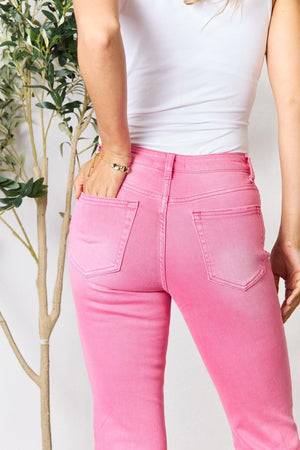 a woman in a white tank top and pink jeans