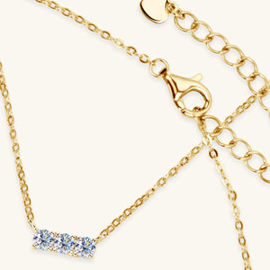 a gold necklace with three diamonds on it
