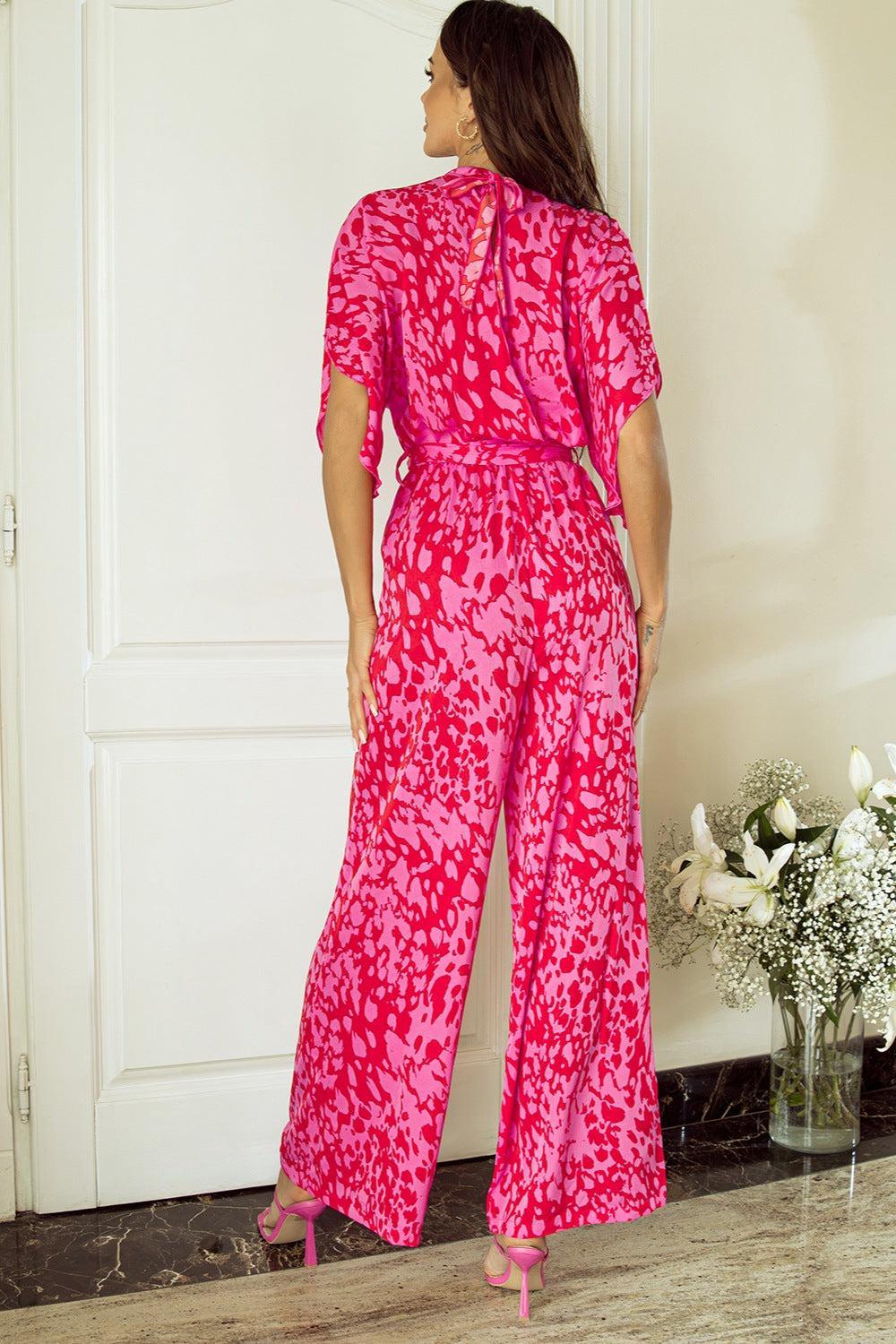 a woman standing in front of a door wearing a pink jumpsuit