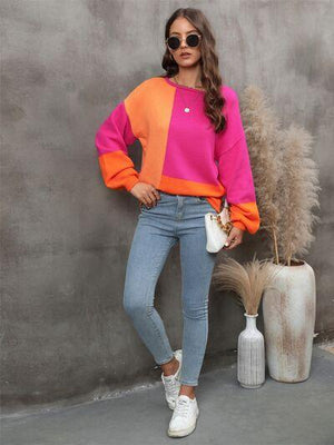 a woman standing next to a plant wearing a pink and orange sweater