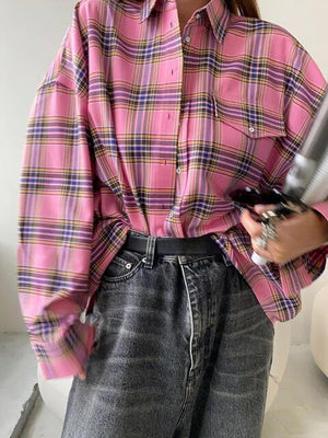 a woman wearing a pink plaid shirt and jeans