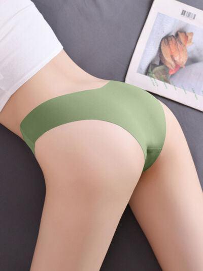a woman laying on top of a bed wearing a green panties