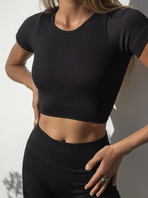 a woman wearing a black crop top and black pants