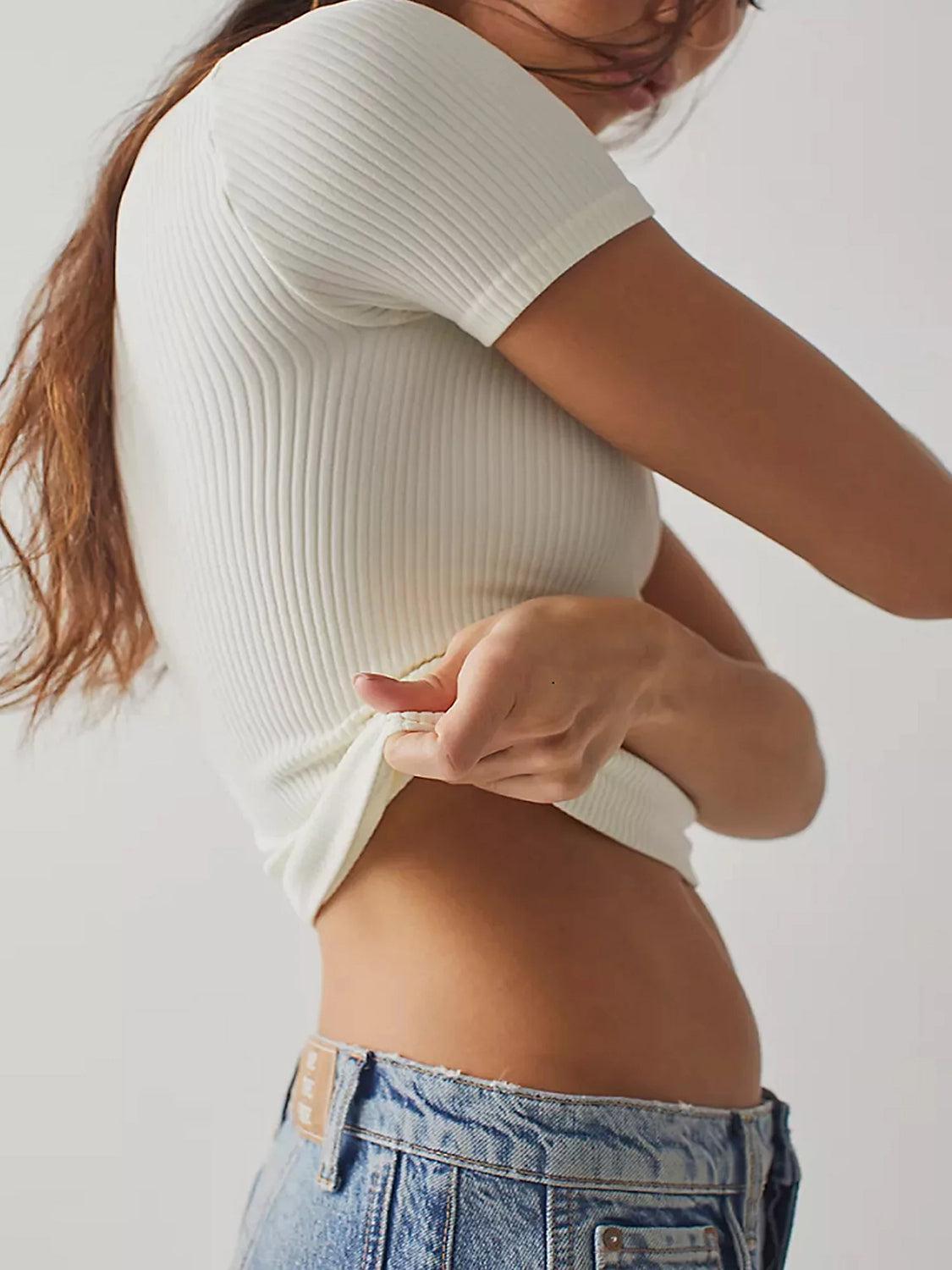 a woman in a white top is holding her stomach