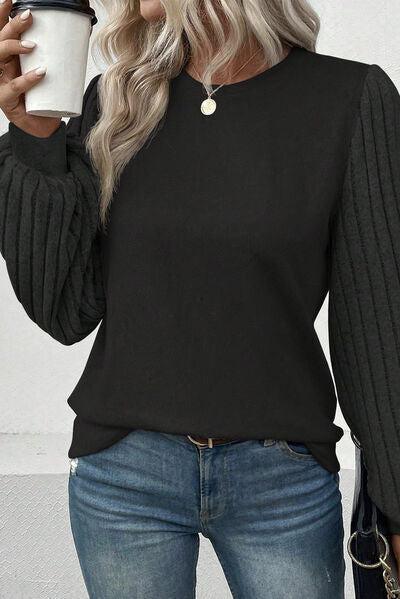 a woman holding a coffee cup and wearing a black sweater