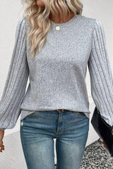 a woman wearing a gray sweater and jeans