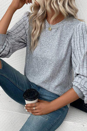 a woman sitting on a wall holding a cup of coffee