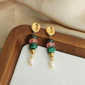 a pair of earrings sitting on top of a wooden tray