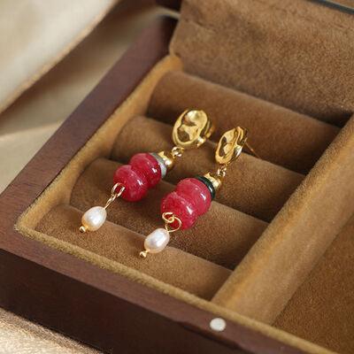 a pair of red and white earrings in a wooden box