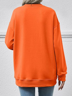 a woman wearing an orange sweatshirt and jeans